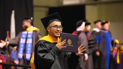 A man is walking with a smile, holding his degree in his hands.