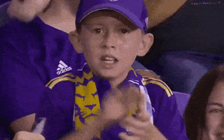 Video gif. Young boy shakes his head intently as he mouths the words, "Let's go," clapping his hands fiercely and throwing a fist in the air.