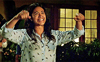 TV gif. Gina Rodriguez as Jane Villanueva in Jane the Virgin, pumps her fists in elated celebration, moonwalking away with tears of joy in her eyes.