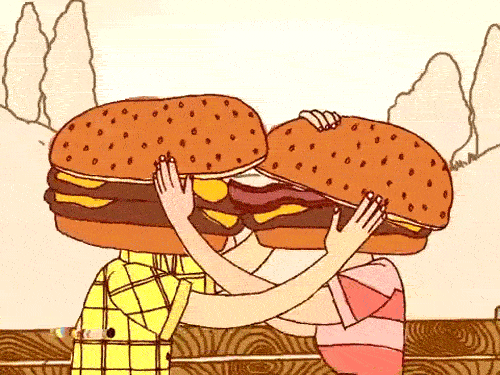 Cartoon gif. Couple with giant cheeseburgers for heads caress each other's faces, engaging in a passionate makeout sesh that involves one of their bacon tongues.