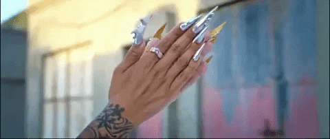 Music video gif. From Rosalía's video for Aute Cuture, two hands with long, sharp chrome nails clap.