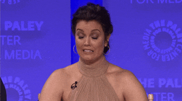Video gif. Actress Bellamy Young, in red carpet attire, crosses her fingers on both hands and looks to the sky, hoping for a good outcome.