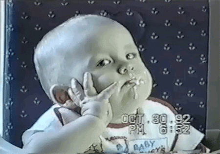 TV gif. AFV video of a bored-looking baby with food all over his mouth rests his head against his hand as he gives us the side eye. As a spoonful of porridge enters the frame, he opens his mouth for an uninterested bite.