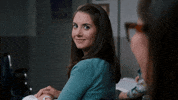 TV gif. Alison Brie as Annie Edison on Community turns around in her seat to look at a girl behind her. She gives a big smile and thumbs up, and then turns back around awkwardly.