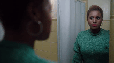 TV gif. Issa Rae on Insecure looks at herself in the mirror in her bathroom and winks at herself to give herself confidence.