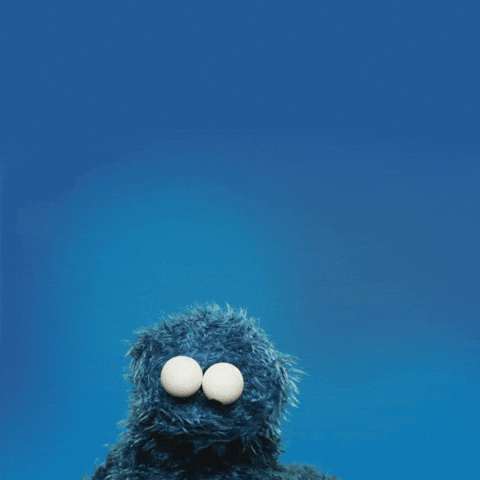 gif of Cookie Monster on a blue background. He holds up a chocolate chip cookie, looks at it, then devours it. Text reads, "Cookie!"