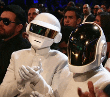 Celebrity gif. Members of Daft Punk sit in the audience at the Grammys, clapping along with everyone.
