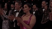 Oscars 2024 GIF. America Ferrera, at the Oscars, smiles to herself as she applauds.