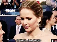 Celebrity gif. Jennifer Lawrence on a red carpet event leans into a reporter's microphone and asks, 