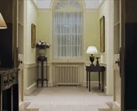 Movie gif. In a scene from Love Actually, we see an empty residential hallway, then Hugh Grant as The Prime Minister shimmies gleefully from one doorway to another.