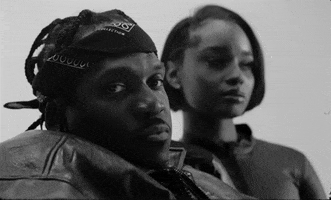 Video gif. Musician Pusha T looks at us and slowly nods. 