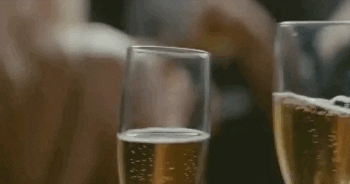 Video gif. Two hands clink champagne glasses together.