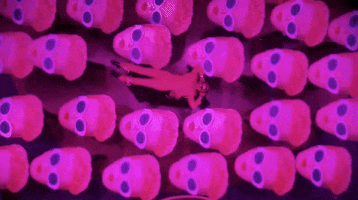 Oscars 2024 GIF. Bird’s eye view of Ryan Gosling, dressed in a Barbie pink tuxedo and sunglasses, lifted in the air, surrounded by Barbie heads.