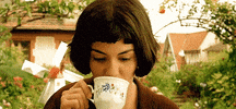 Movie gif. Audrey Tautou as Amelie Poulain in Amelie looks to the side and takes quick sips from a tea cup on loop.
