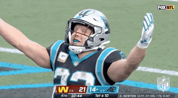 Sports gif. Christian McCaffrey on the Carolina Panthers raises his hands out to the audience, calling for praise after a big play, slapping his chest, as PJ Walker walks up to him smiling. 