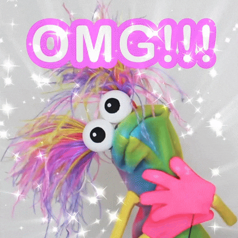 Digital art gif. A tie dyed sock puppet with arms and pink hands and two colorful ponytails sprouting from its head. We zoom on its googly eyed face as it gasps. Sparkles fill the air in amazement. Text, “OMG!!!”