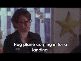TV gif. Tina Fey as Liz and Alec Baldwin as Jack in 30 Rock come together for a hug. Liz opens her arms out, saying, "Hug plane coming in for a landing." Then Jack, clearly in need of a hug, nods his head quickly and steps into the hug.
