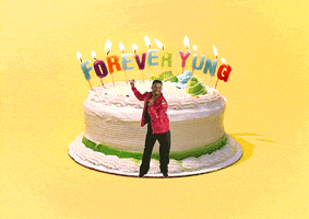 Video gif. Alfonso Ribeiro does the Carlton dance, swinging his arms around and moving his legs in and out, in front of a huge cake that has candles that spell out, “Forever yung.”