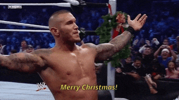 Sport gif. Randy Orton from WWE addressing a crowd with his arms outstretched and a smirk on his face. He yells out, "Merry Christmas," while shaking his head in joy.