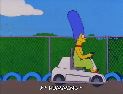 Marge Simpson being passed on a go-kart track by the family
