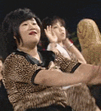 Video gif. Women wearing cheetah-print outfits dance and shake their hips.