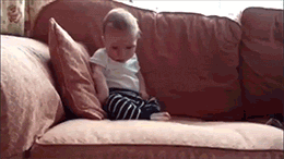 Video gif. A sleepy baby sitting on a couch falls face forward on the couch.
