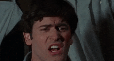 Movie gif. We see a close-up of Bruce Campbell as Ash in The Evil Dead with dark hair, his mouth contorted into a distressed "O," his top teeth showing as his brow furrows.