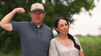 Chip Gaines flexing his arm while Joanna looks back at him with a blank expression