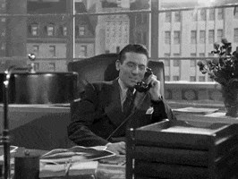 Movie gif. A man in Christmas in Connecticut sits in a handsome leather chair in an office, cigarette in hand and corded phone to his heart. He smiles as he says into the phone, "May I wish you a Merry Christmas?"