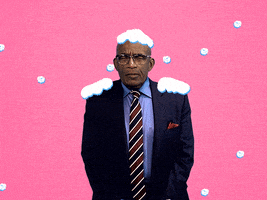 Reaction gif. Al Roker in a navy blue suit with cartoon snow falling around him and building up on his shoulders and on top of his head. He gives an exaggerated shiver to pretend that he’s cold from the snow.