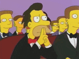 The Simpsons gif. Lenny wears a tux and clasps his hands with pointers up at his mouth as he blinks patiently.