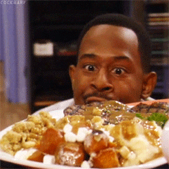 TV gif. Martin Lawrence on the Martin show lowers his face to a plate of Thanksgiving dinner. Wide-eyed, he waves his hand towards his face, taking a big excited sniff of the feast.