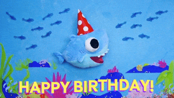 Digital illustration gif. Baby Shark stuffie swims across the bottom of the ocean floor wearing a red and white polka dot birthday hat that slides on and off its head. He's edited to look like his fins are moving as he bobs up and down in the water, giving the appearance of swimming. Fish pass by and bubbles emerge from the bottom. Text, "Happy Birthday!'