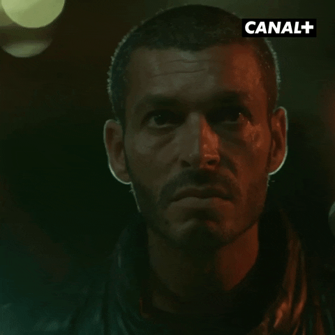 TV gif. Franck Gastambide on Validé subtly smiles evilly, but his face quickly drops into a menacing scowl. Red lighting glows off of his face, making him appear more intimidating.