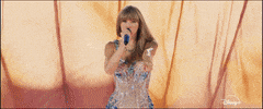 Celebrity gif. A montage of Taylor Swift during the Eras Tour wearing different outfits as she sings and points at us. 
