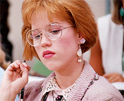 Movie gif. Molly Ringwald as Andie in Pretty in Pink glances over and rolls her eyes, then turns her attention forward.